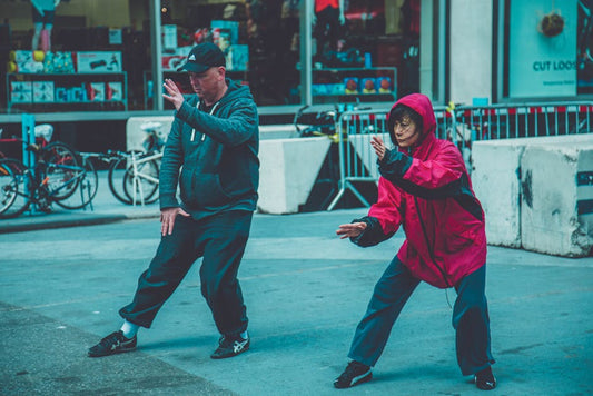 Two adults practicing martial arts on the street, showcasing fitness and focus in an urban environment.