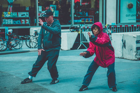 Two adults practicing martial arts on the street, showcasing fitness and focus in an urban environment.