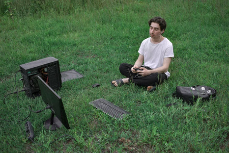 Man using computer outdoors on grass, embracing digital nomad lifestyle.