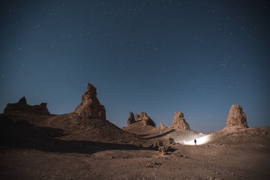A lone explorer at Trona Pinnacles under a clear starry sky.