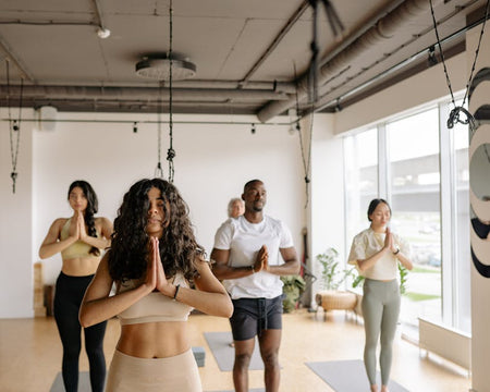 A multicultural group of adults practicing yoga poses together in a bright studio.